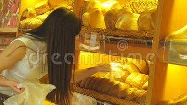 女人选择并把一个新鲜的面包放进超市的包裹里。 小女孩拿着一条面包